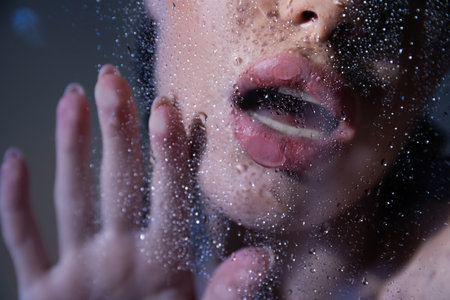 Cropped view of sexy woman touching glass with water drops on grey backgroundの写真素材