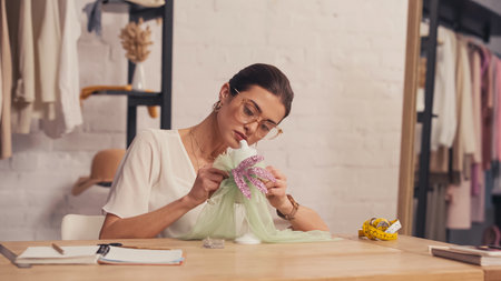 Designer making dress on small mannequin near notebooks in atelier
