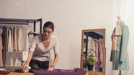 Designer touching cloth near sewing machine and mannequin in atelier