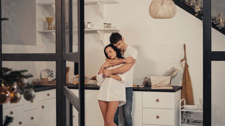 pleased man with closed eyes embracing sensual girlfriend in white shirtの写真素材