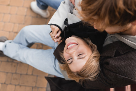 top view of redhead man embracing happy blonde woman smiling in parkの写真素材