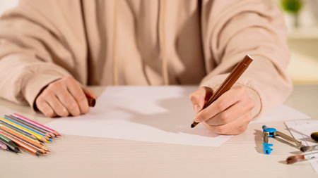 Cropped view of woman holding marker near paper and color pencils