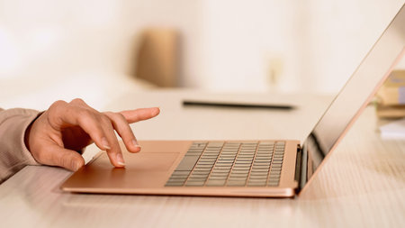 Cropped view of freelancer using laptop touchpad on desk