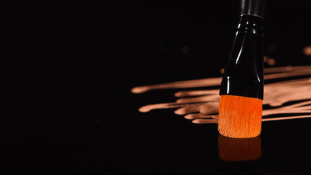 Close up view of cosmetic brush near blurred makeup foundation on black backgroundの写真素材