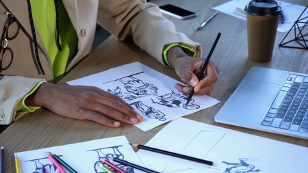 Cropped view of african american designer drawing sketches near devices and paper cup in studioの写真素材