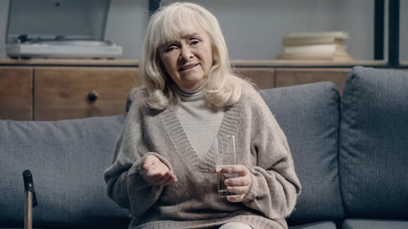 sad senior woman with dementia holding pills and looking at camera