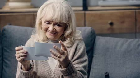 happy senior woman with dementia holding printed photographs at home