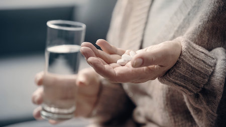 partial view of senior woman with dementia holding pills and glass of waterの写真素材