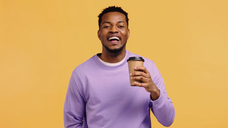 cheerful african american man in purple pullover holding paper cup with coffee to go isolated on...