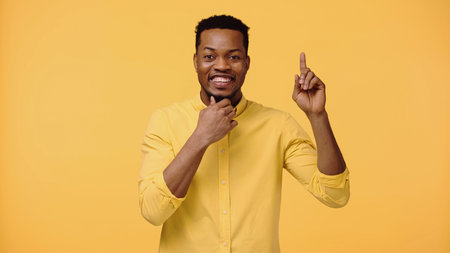 happy african american man smiling while having idea isolated on yellow