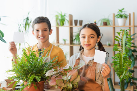 Preteen kids holding sticky notes near plants at homeの写真素材