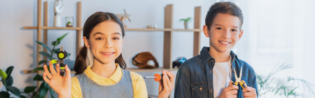 happy kids with tools and mechanical part smiling at camera at home, banner