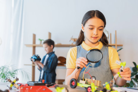 Kid holding magnifying glass and robotic model on table at home