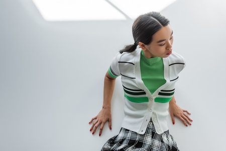 Top view of asian model in striped cardigan posing on grey background with lightの写真素材
