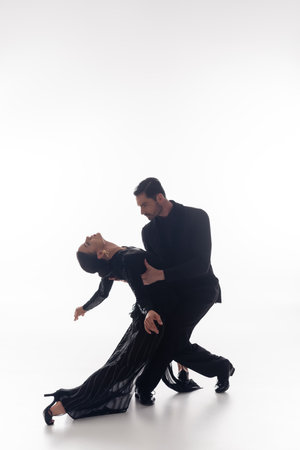 Couple in suit and dress performing tango on white backgroundの写真素材