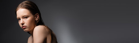 Young model with wet face and shoulders looking at camera on grey background, bannerの写真素材