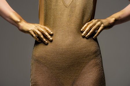 Cropped view of woman in golden dress and paint on skin posing isolated on greyの写真素材
