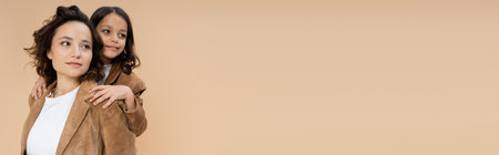 brunette girl and woman in stylish suede jackets looking away isolated on beige, bannerの写真素材