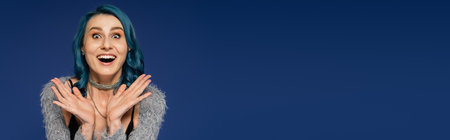 astonished woman with open mouth looking at camera and showing wow gesture isolated on blue, bannerの写真素材