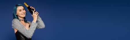 happy and trendy woman with bottle of champagne isolated on blue, banner