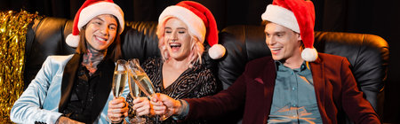 cheerful nonbinary people in santa hats celebrating christmas and clinking champagne glasses of dark...