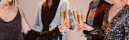 partial view of stylish nonbinary friends clinking champagne glasses on grey background, bannerの写真素材