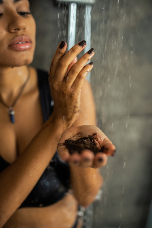 Cropped view of african american woman holding coffee scrub under water in shower at homeの写真素材