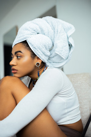 pretty african american woman with towel on head looking away at home