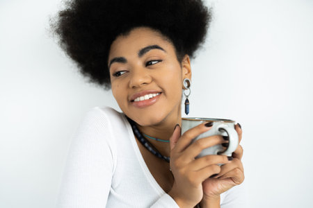 cheerful african american woman holding cup of coffee isolated on whiteの写真素材
