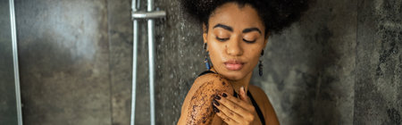Young african american woman massaging body with scrub in shower cabin, banner
