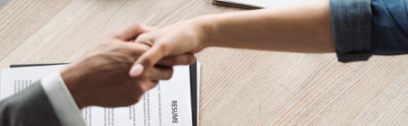 Top view of resume near job seeker and businessman shaking hands in office, banner