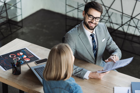High angle view of cheerful businessman holding resume near candidate in officeの写真素材