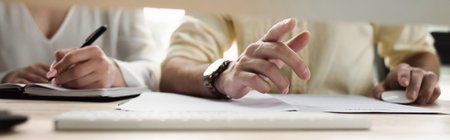 Cropped view of businessman pointing near intern writing on notebook in office, bannerの写真素材