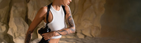 partial view of tattooed archaeologist with gun in holster, bannerの写真素材