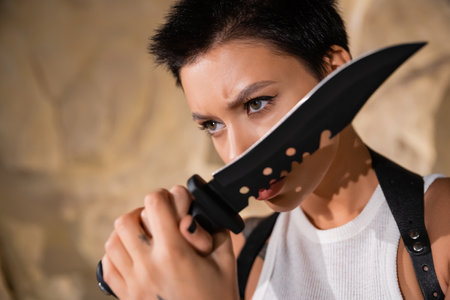 armed and sexy archaeologist with short hair holding sharp knifeの写真素材