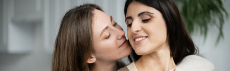 Lesbian woman hugging and kissing partner at home, bannerの写真素材