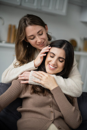 Young lesbian woman touching brunette girlfriend on couch