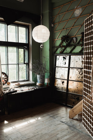 art workshop with large window and decorative lattice near vintage glass under sphere chandelier