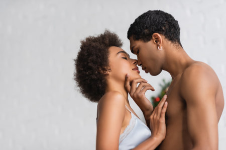 side view of shirtless african american man touching face of sexy girlfriend in bra