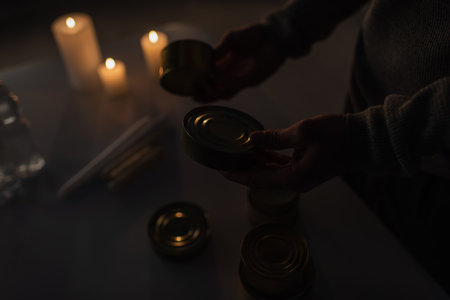 partial view of man with canned food near candles burning during power outageの写真素材