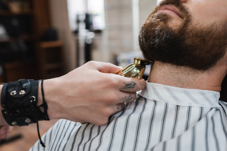 partial view of barber trimming neck of bearded man with hair clipper in barbershopの写真素材