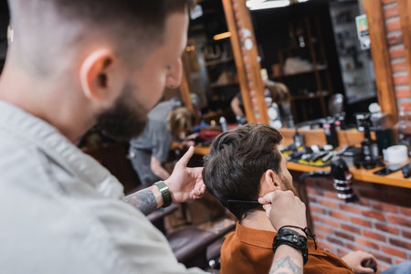 Blurred hairdresser combing hair of man in beauty salonの写真素材