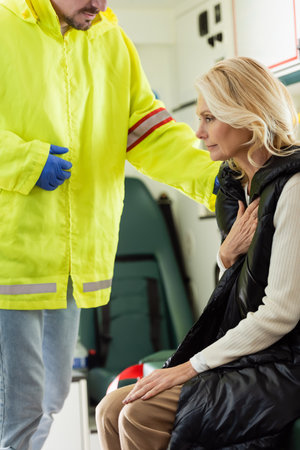 Paramedic in uniform calming mature woman in emergency vehicleの写真素材