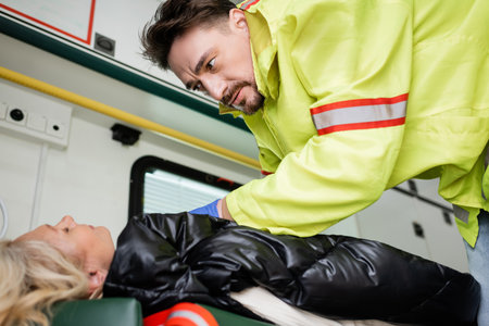 Paramedic in uniform giving first aid to unconscious patient in emergency vehicleの写真素材