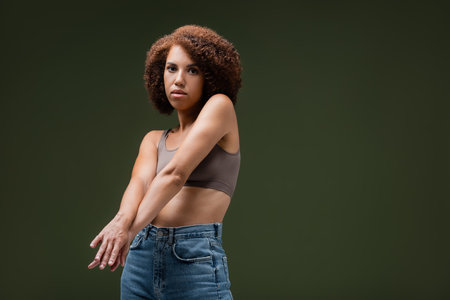African american woman in top posing isolated on dark greenの写真素材