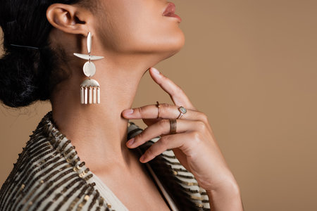 cropped view of young african american woman in luxurious golden jewelry posing isolated on beigeの写真素材