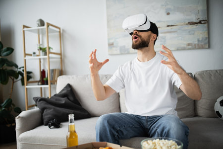 stunned bearded man in vr headset gesturing while gaming in home