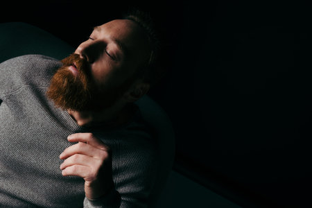 Stylish bearded model posing isolated on black with lighting and shadowの写真素材