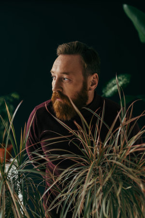 Trendy model in jumper standing near plants isolated on blackの写真素材