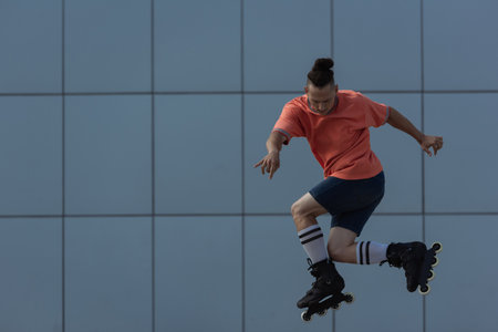 Young roller skater in shorts jumping near blurred building outdoorsの写真素材
